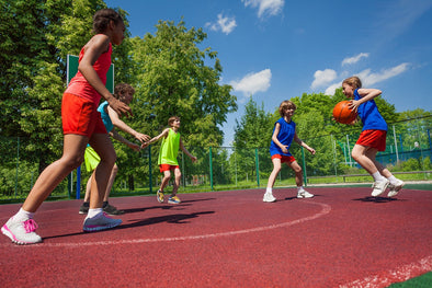 children playing basketball outside in a school yard